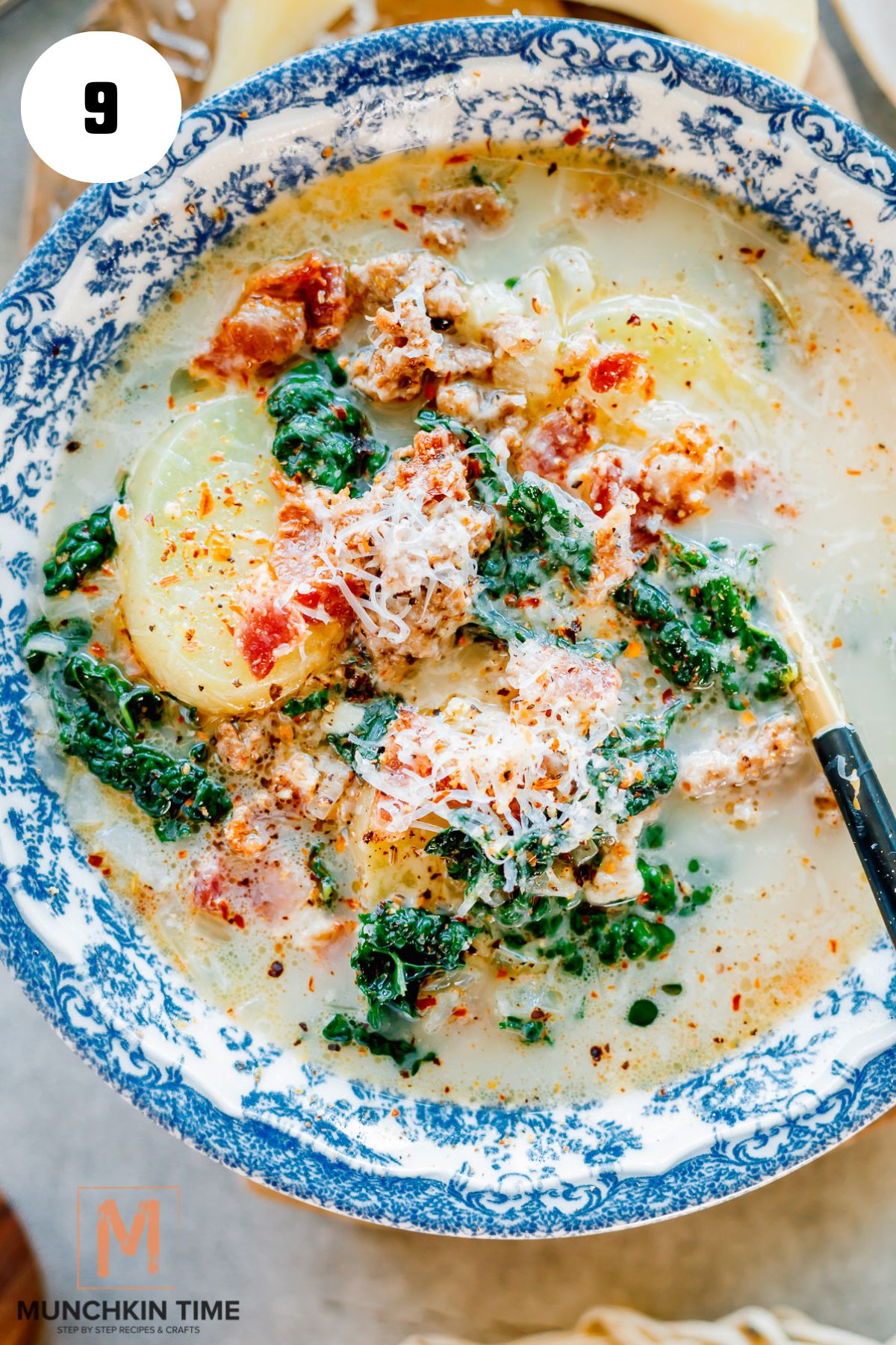 Homemade Zuppa Toscana soup in a blue plate garnished with cheese and red pepper flakes.