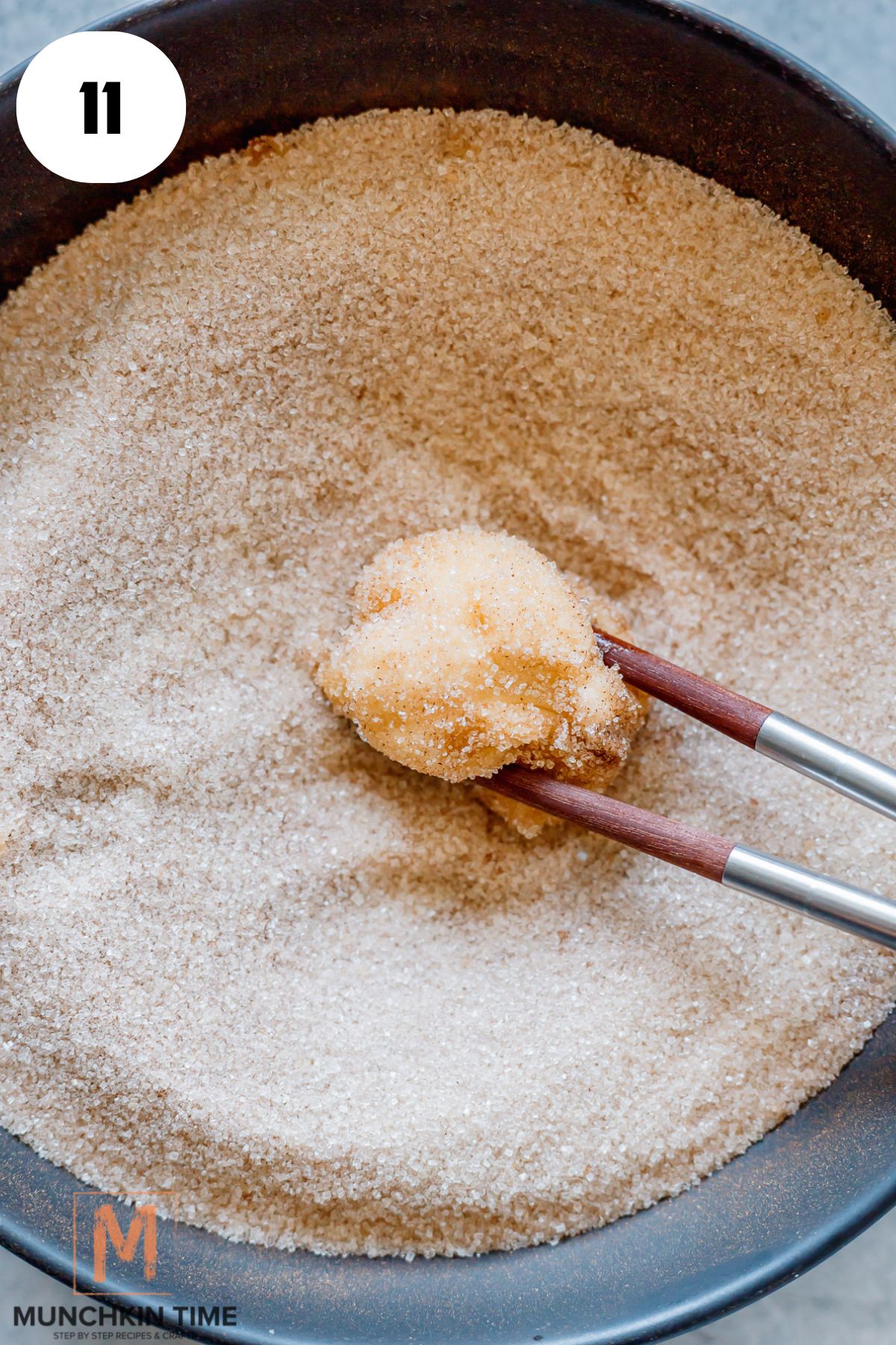 a small dough ball being coated with sugar with cinnamon.
