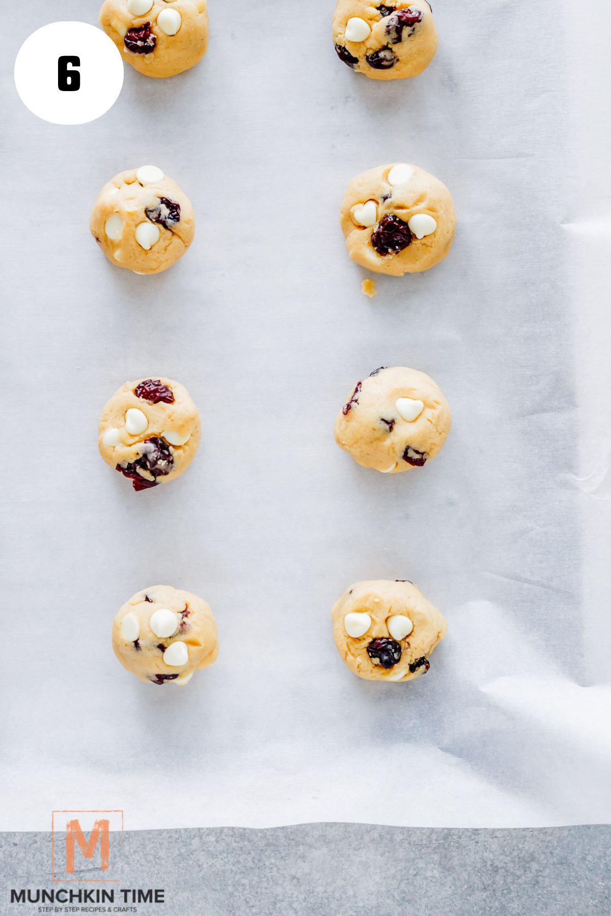 cranberry cookie balls with dried cranberries on a baking sheet ready for baking.