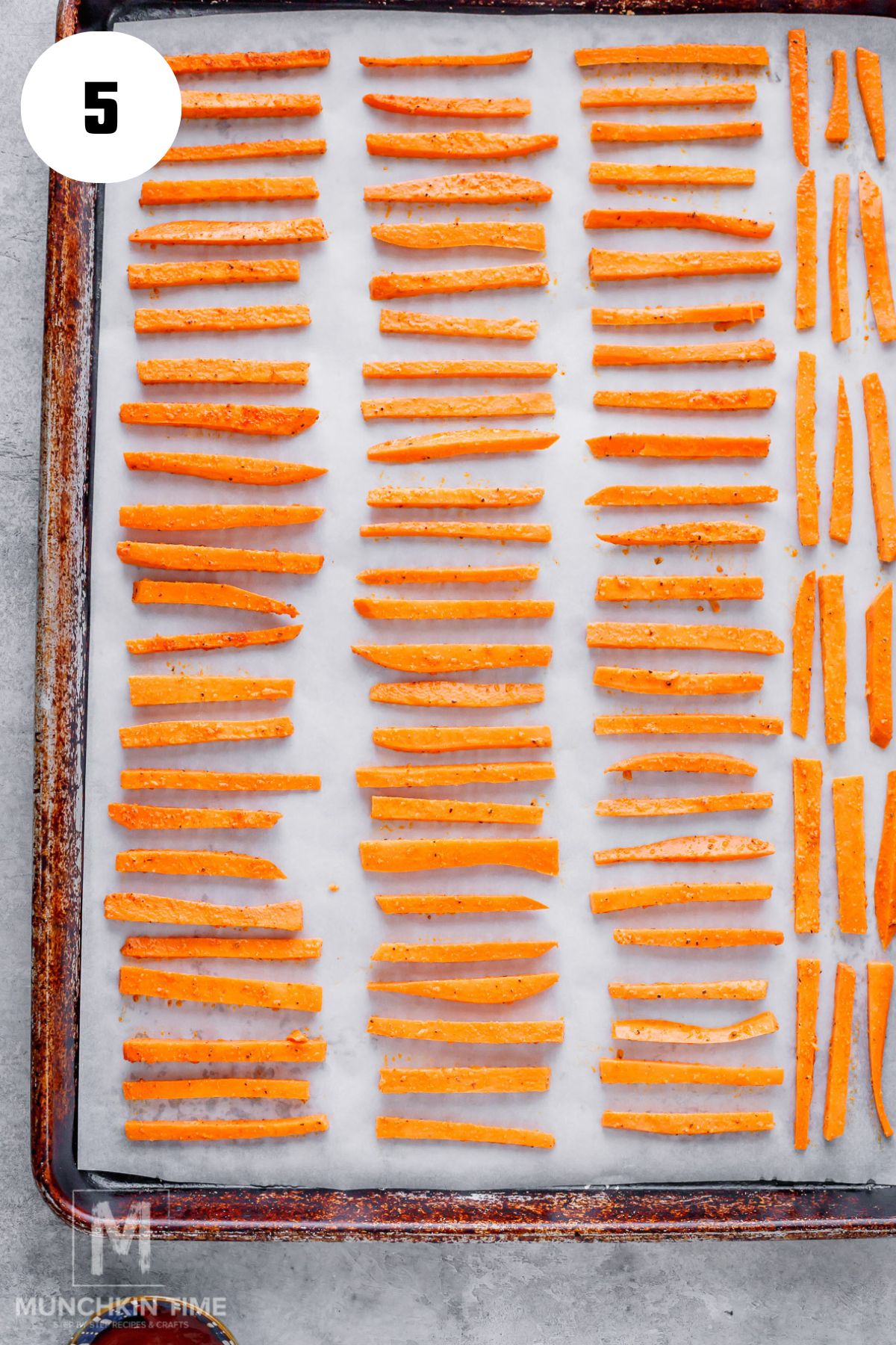 sweet potato strips arranged on a baking sheet lined with parchment paper.