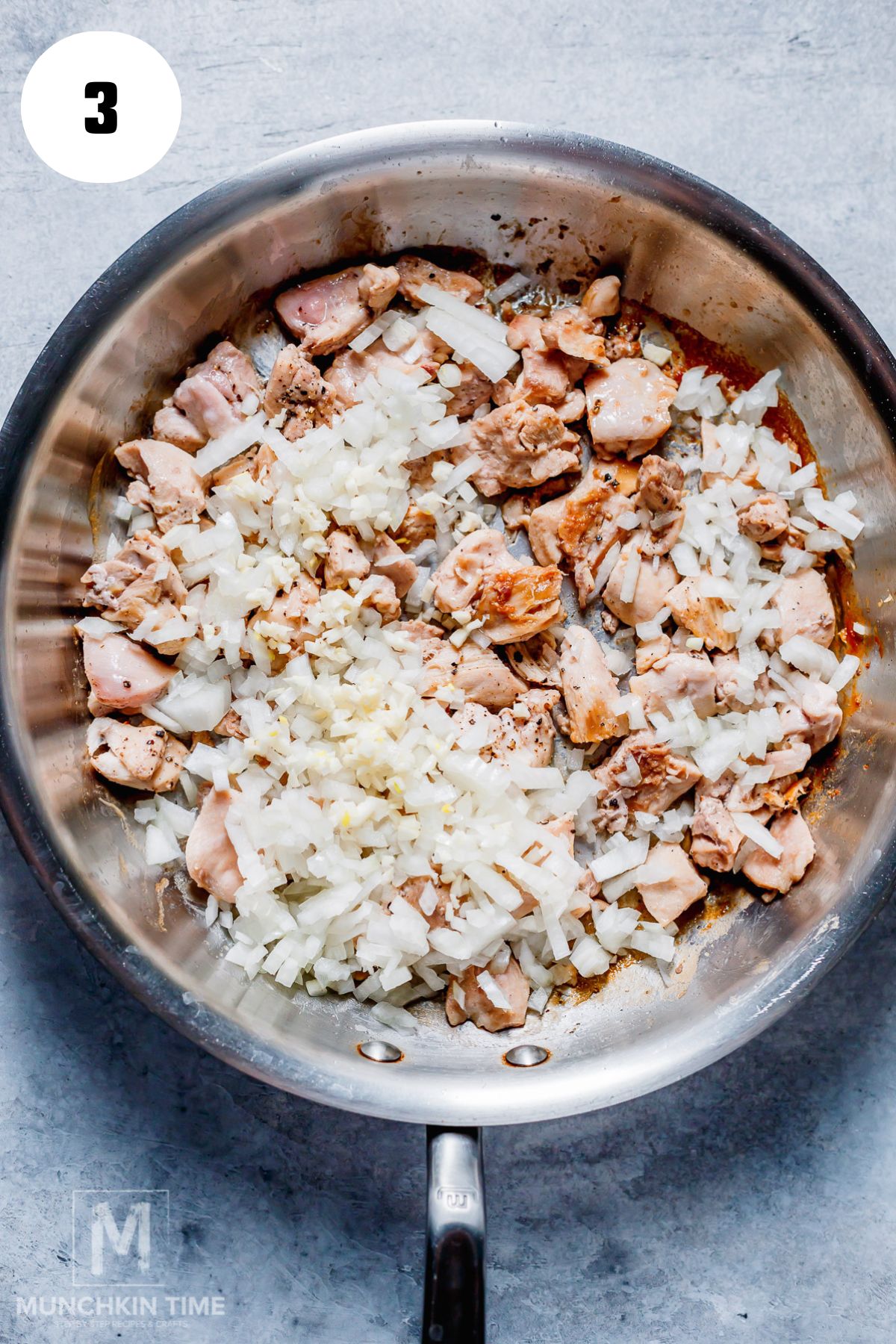 onion and garlic added to the skillet with chicken.