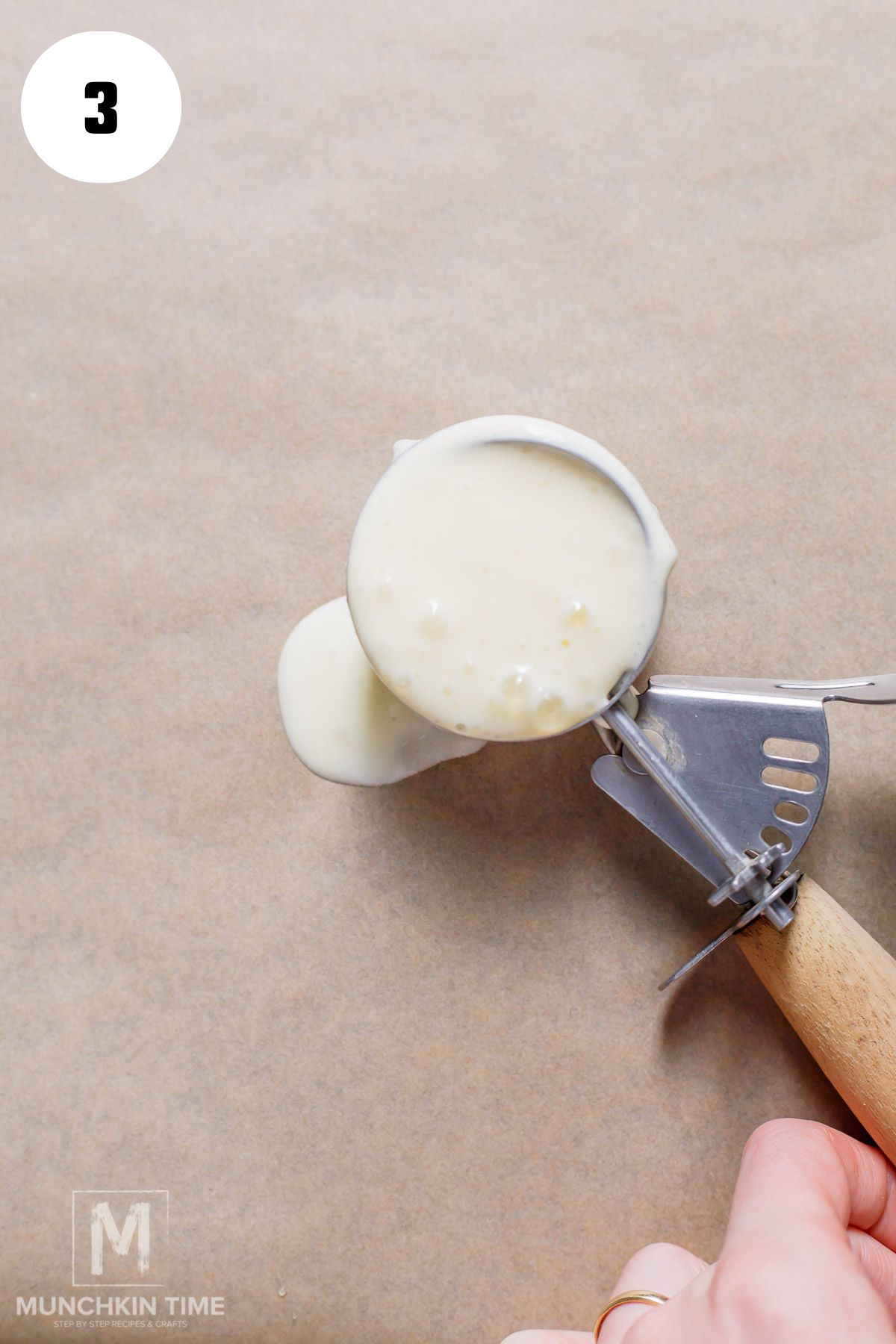 a scoop of cottage cheese batter going onto the parchment paper.