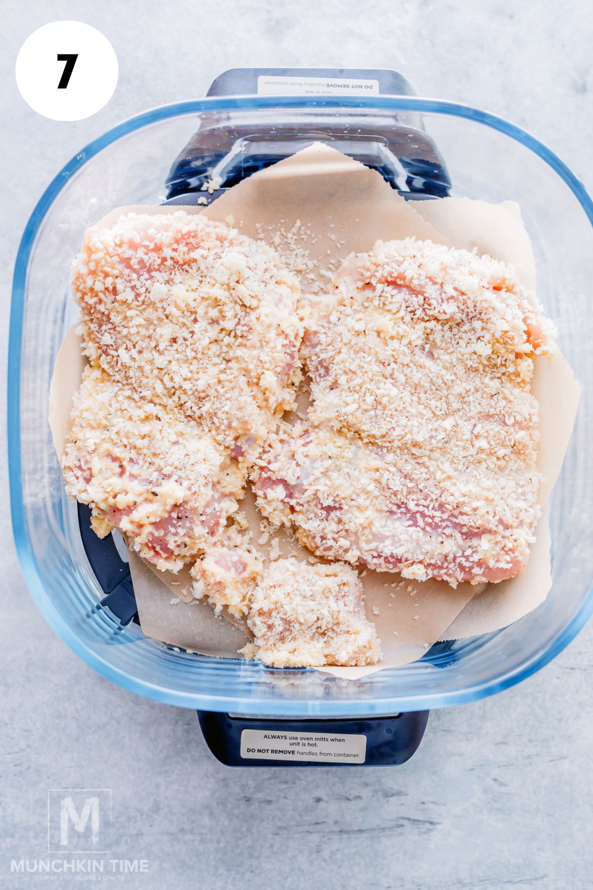 coated chicken thighs placed into the air fryer dish.