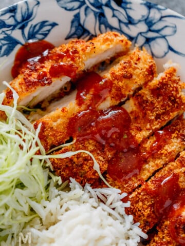 sliced air fryer chicken katsu with sauce on top.