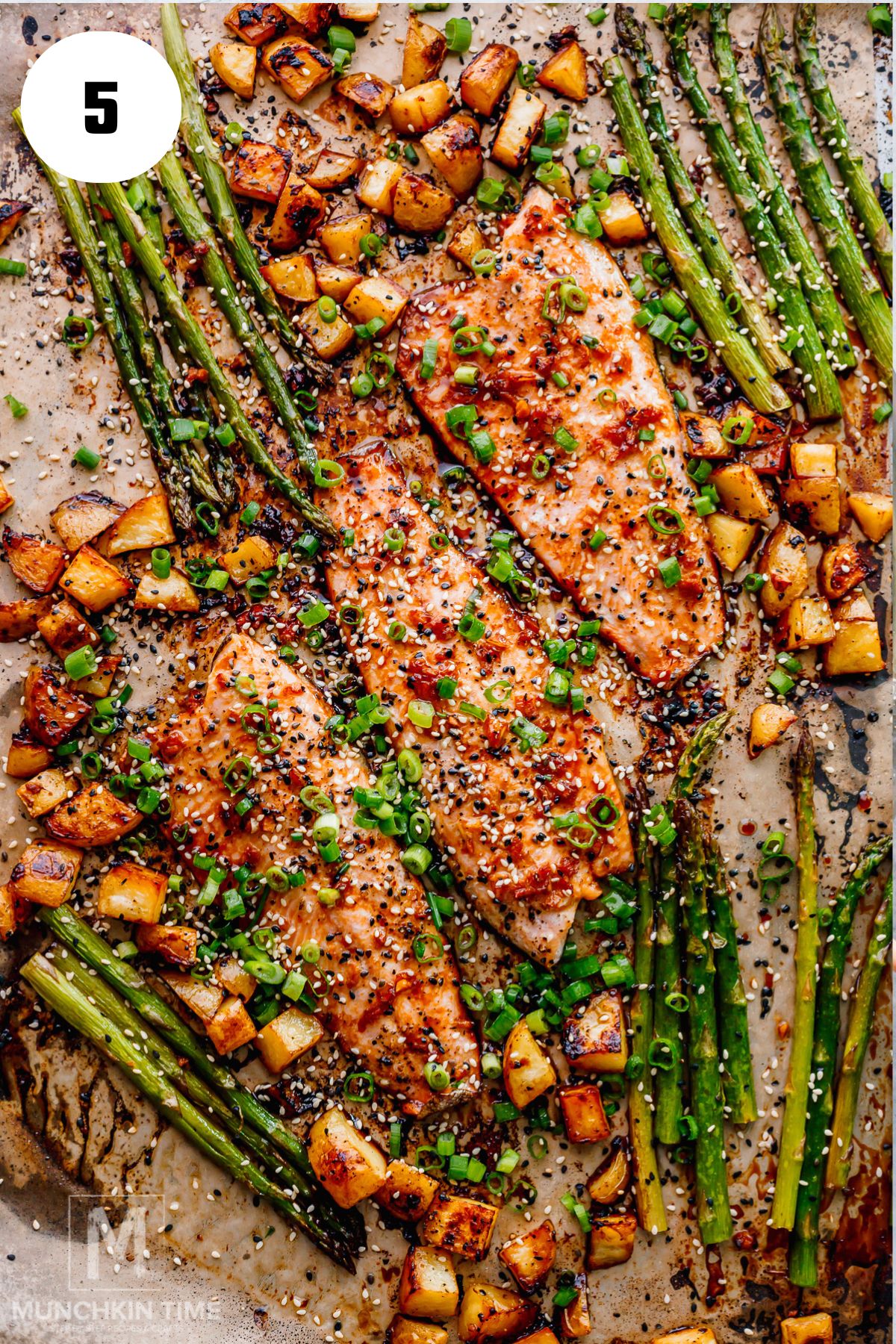 one sheet pan trout with vegetables garnished with green onion and sesame seeds.