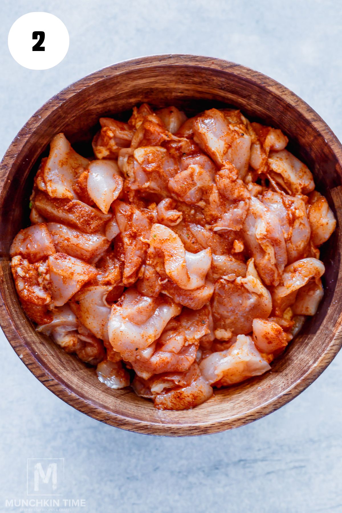 cut chicken mixed with spices in a bowl.