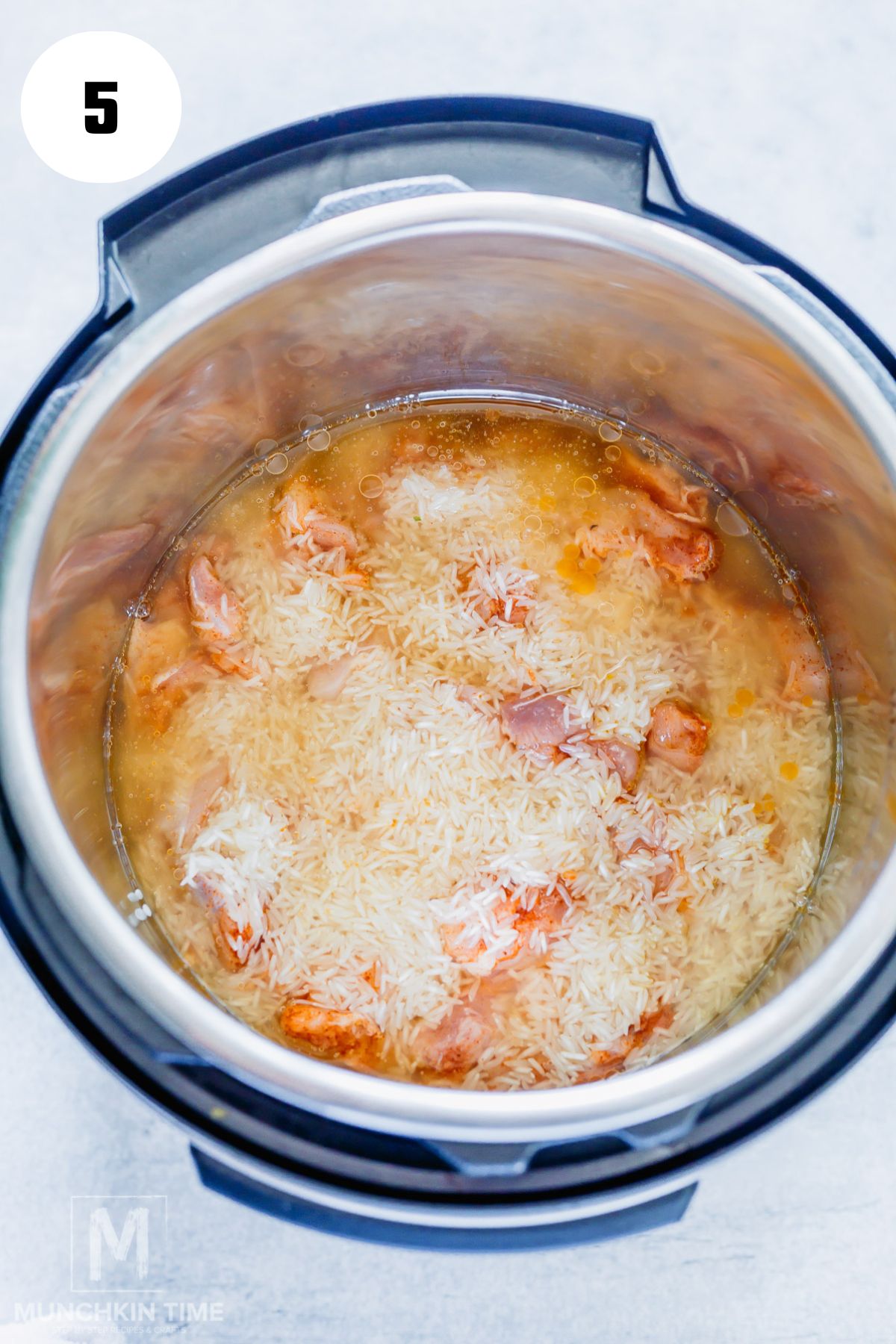 Chicken broth added to the pot with chicken and rice.