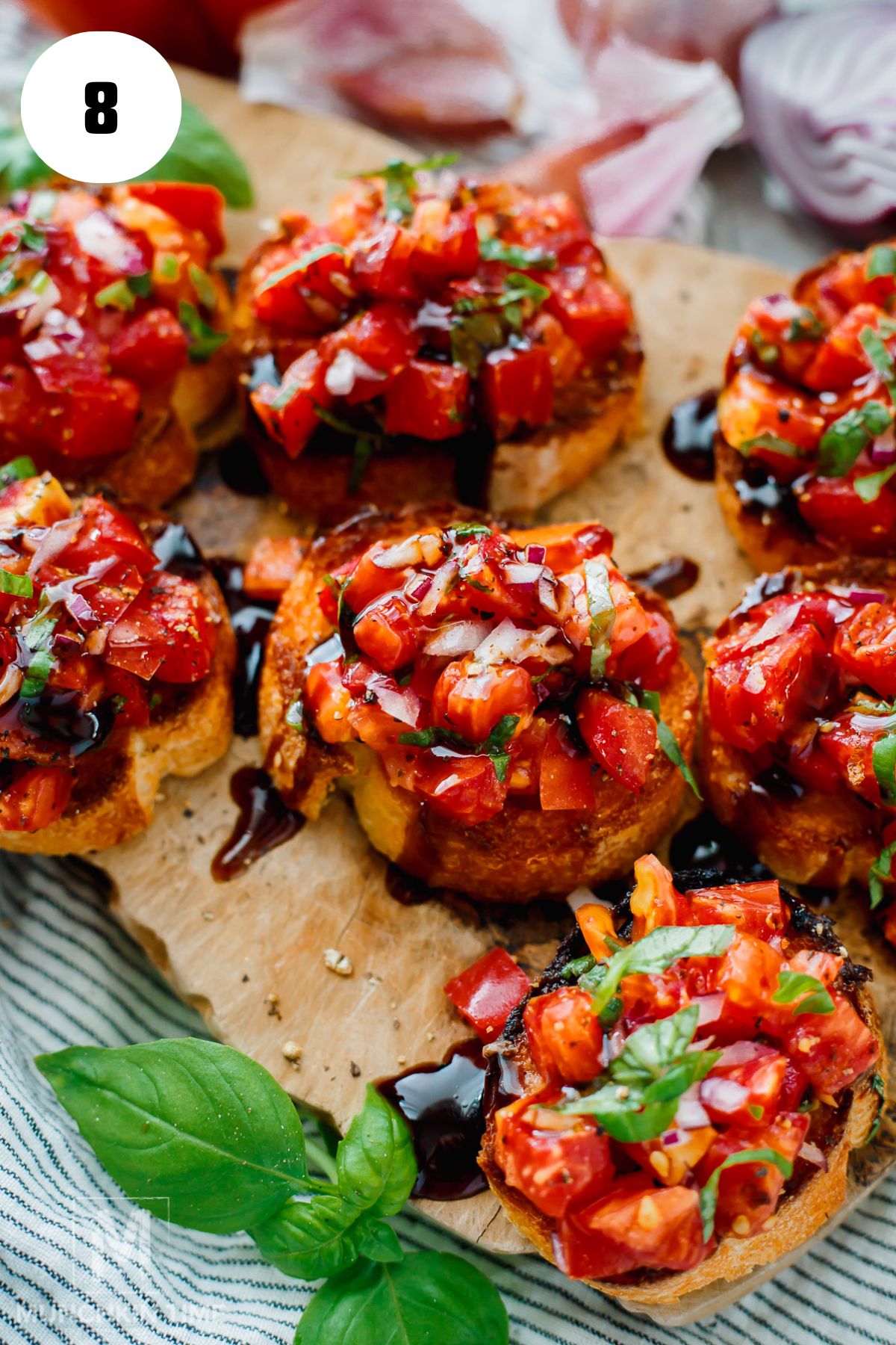 Heirloom tomato bruschetta with fresh basil on toasted baguette slices.