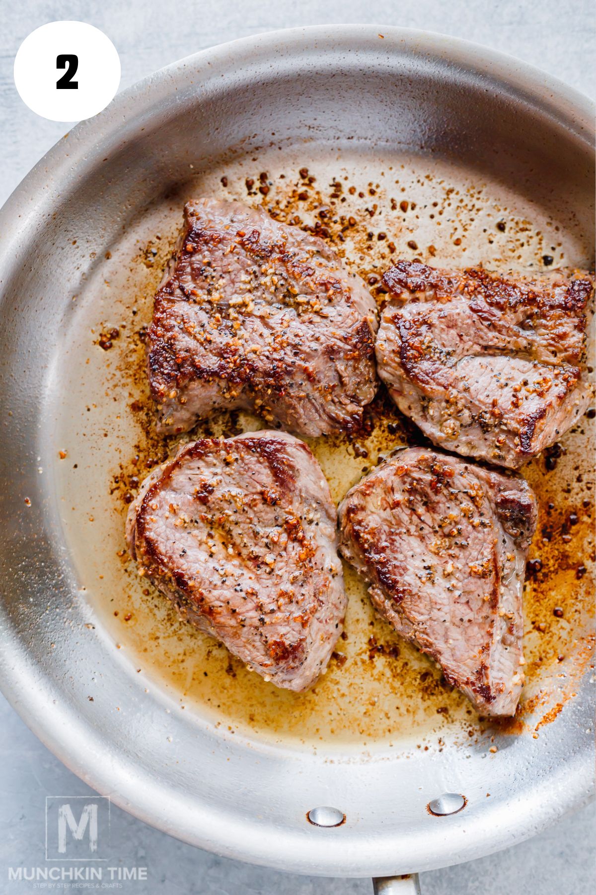 Beef steak searing in a hot skillet until browned.
