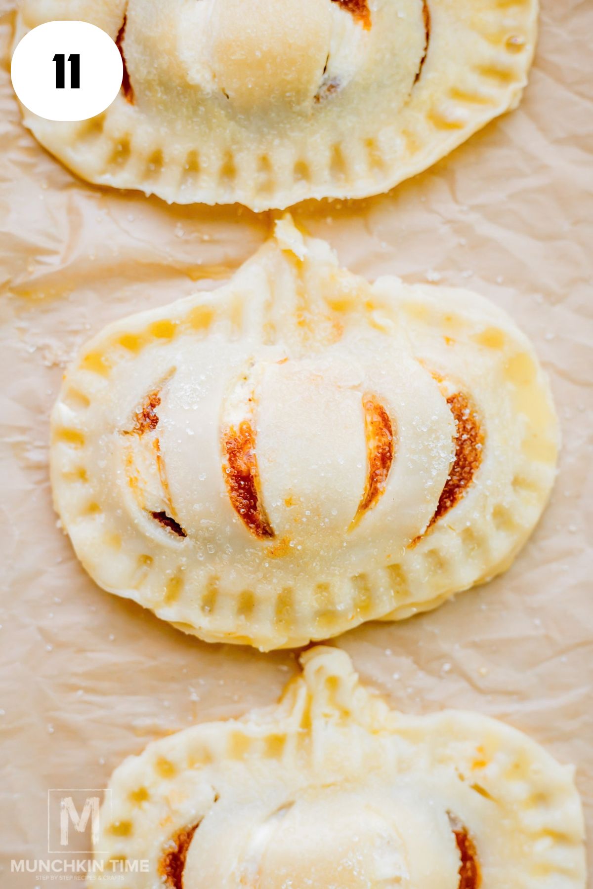 Brushing pumpkin hand pies with egg wash before baking.