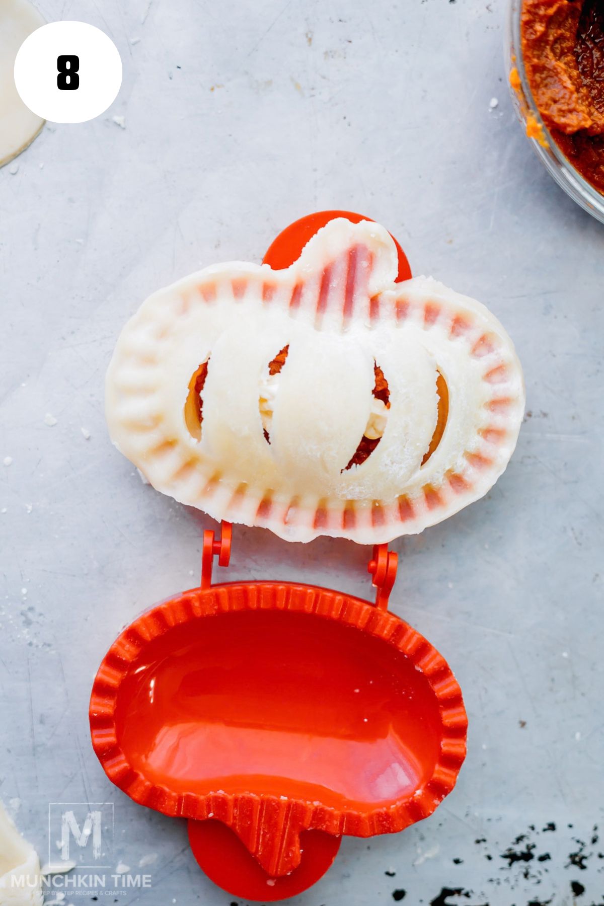 Pumpkin hand pie mold closing around filled pie crust to seal the edges.