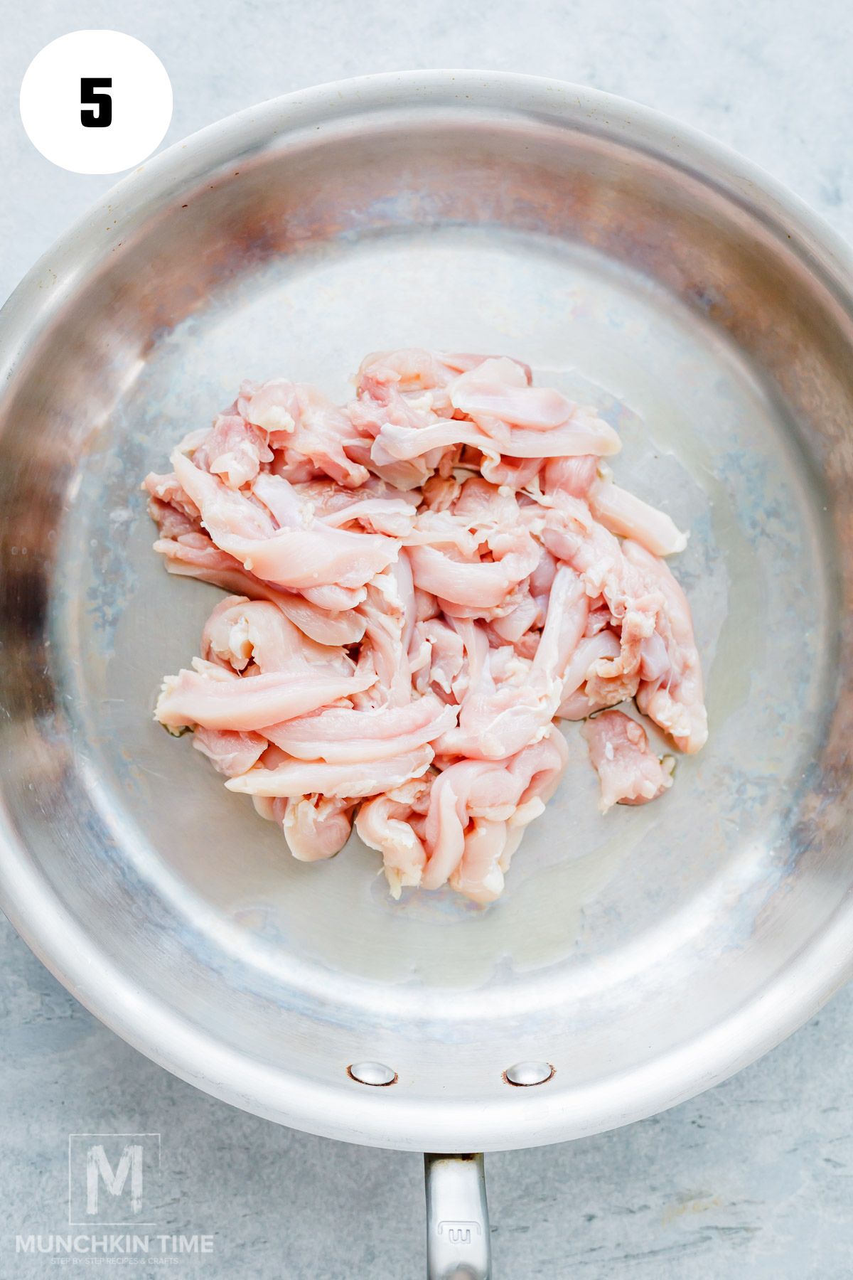 Sliced chicken thighs cooking in a hot skillet.