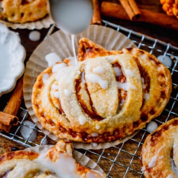 Golden pumpkin hand pies stacked and drizzled with simple glaze for a cozy fall dessert.