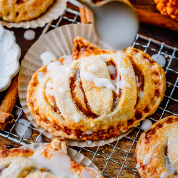 Golden pumpkin hand pies stacked and drizzled with simple glaze for a cozy fall dessert.