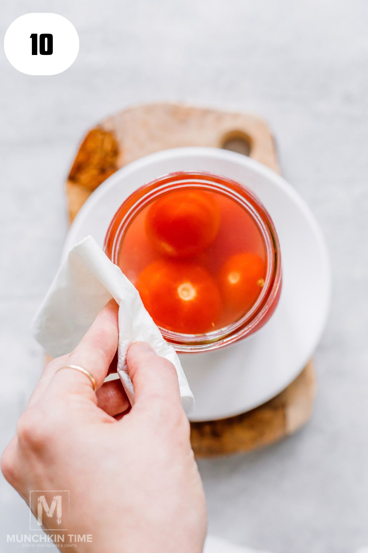 Wiping the rim of a jar with a clean damp paper towel.