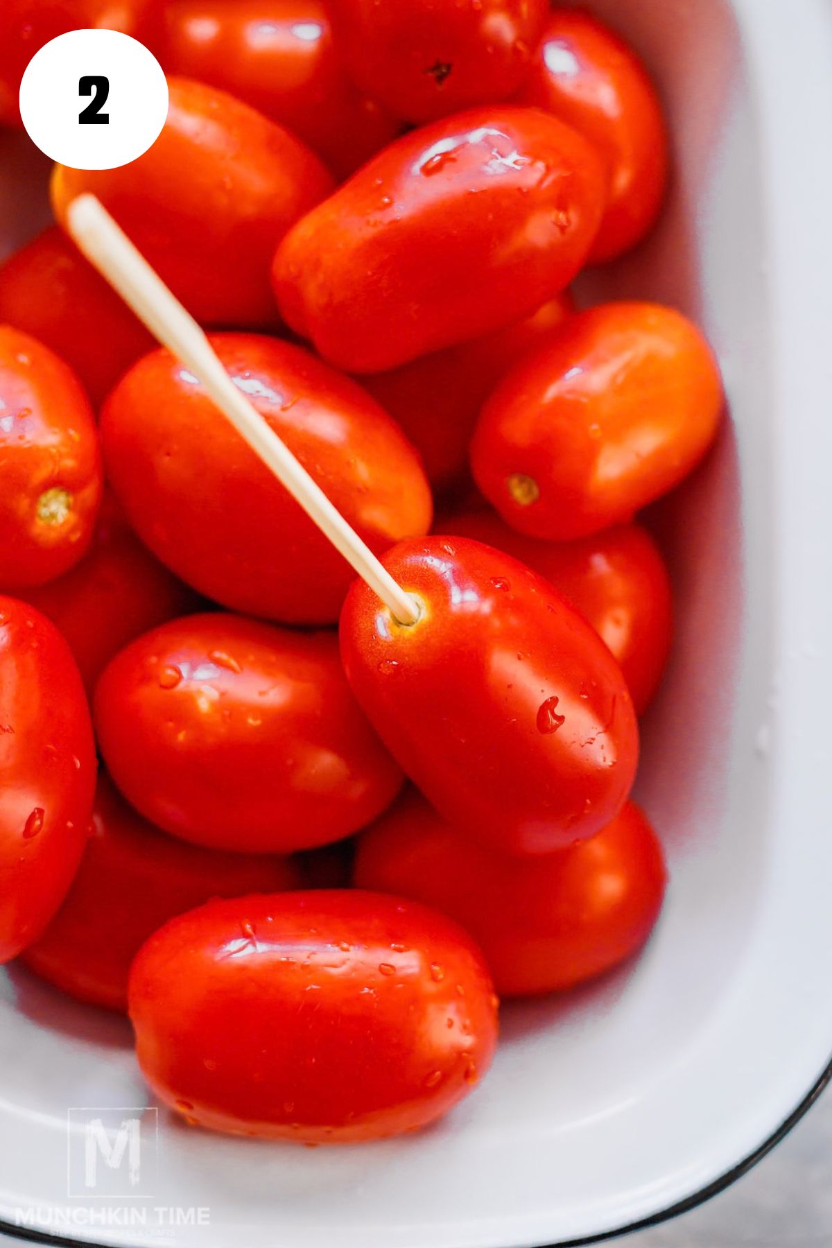 Poking a small hole in Roma tomatoes with a chopstick before pickling