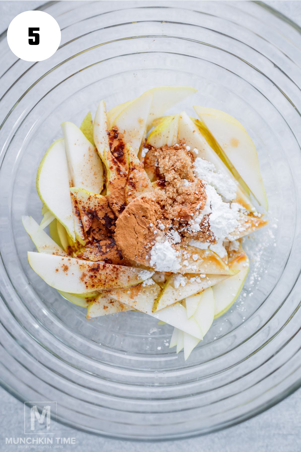 Thinly sliced Bartlett pears in a bowl with brown sugar, cinnamon, and brown butter.