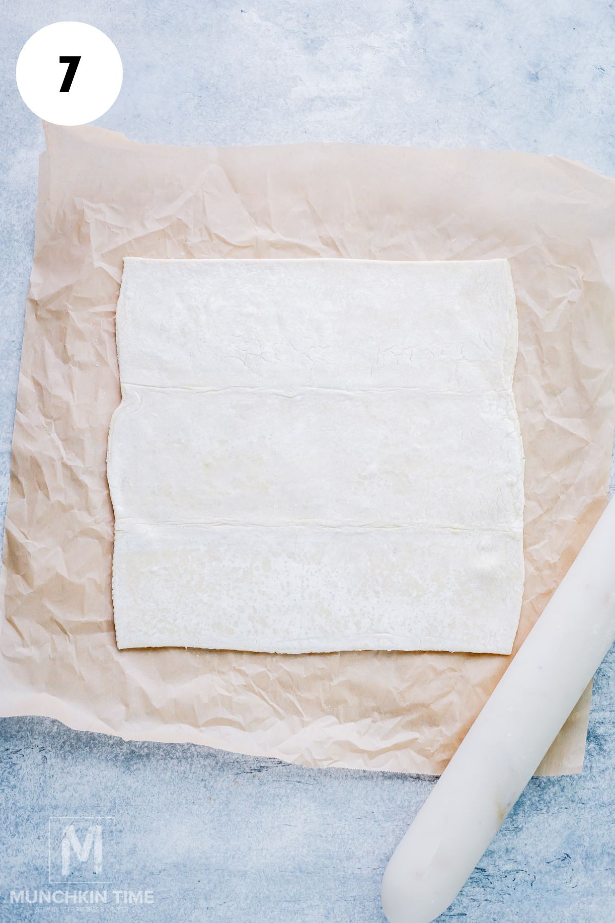 Store-bought puff pastry is rolled on a parchment paper.