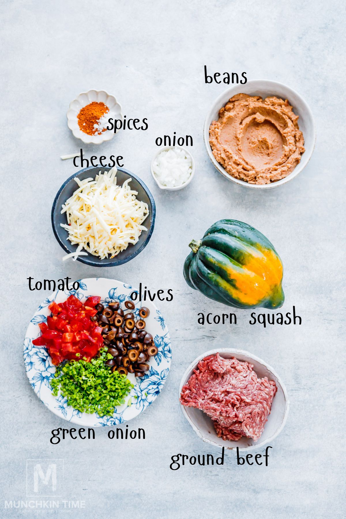 Ingredients for stuffed acorn squash with ground beef, refried beans, taco seasoning, and shredded cheese