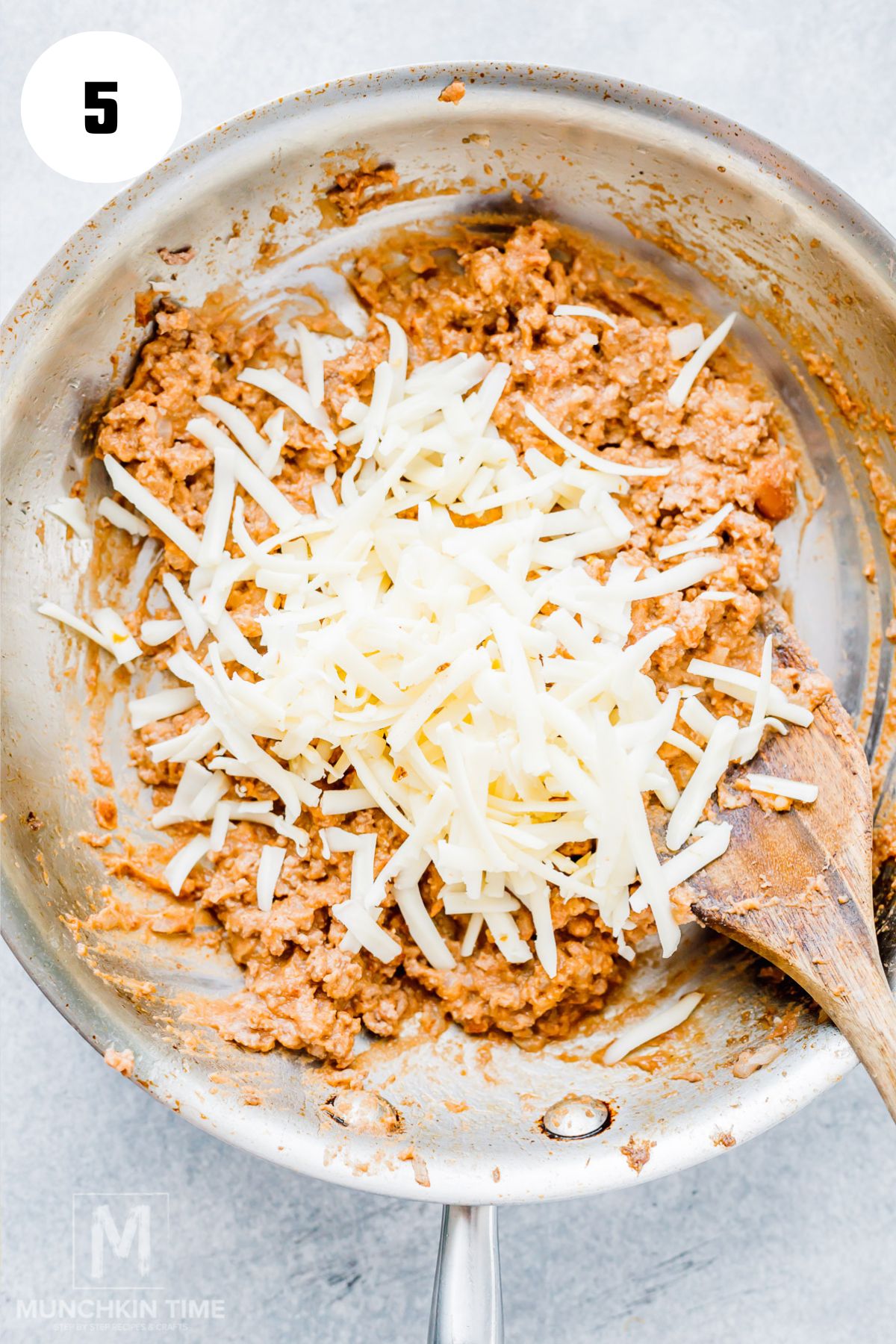 Stirring shredded cheddar and mozzarella cheese into the taco-seasoned ground beef filling