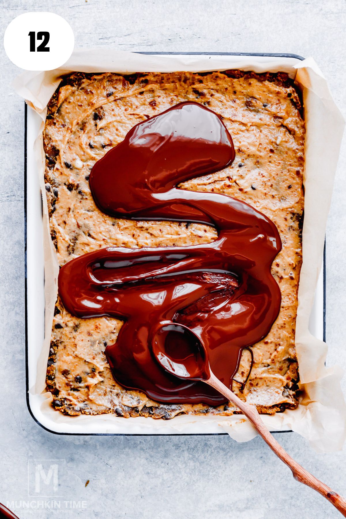Pouring melted dark chocolate over date caramel protein bars