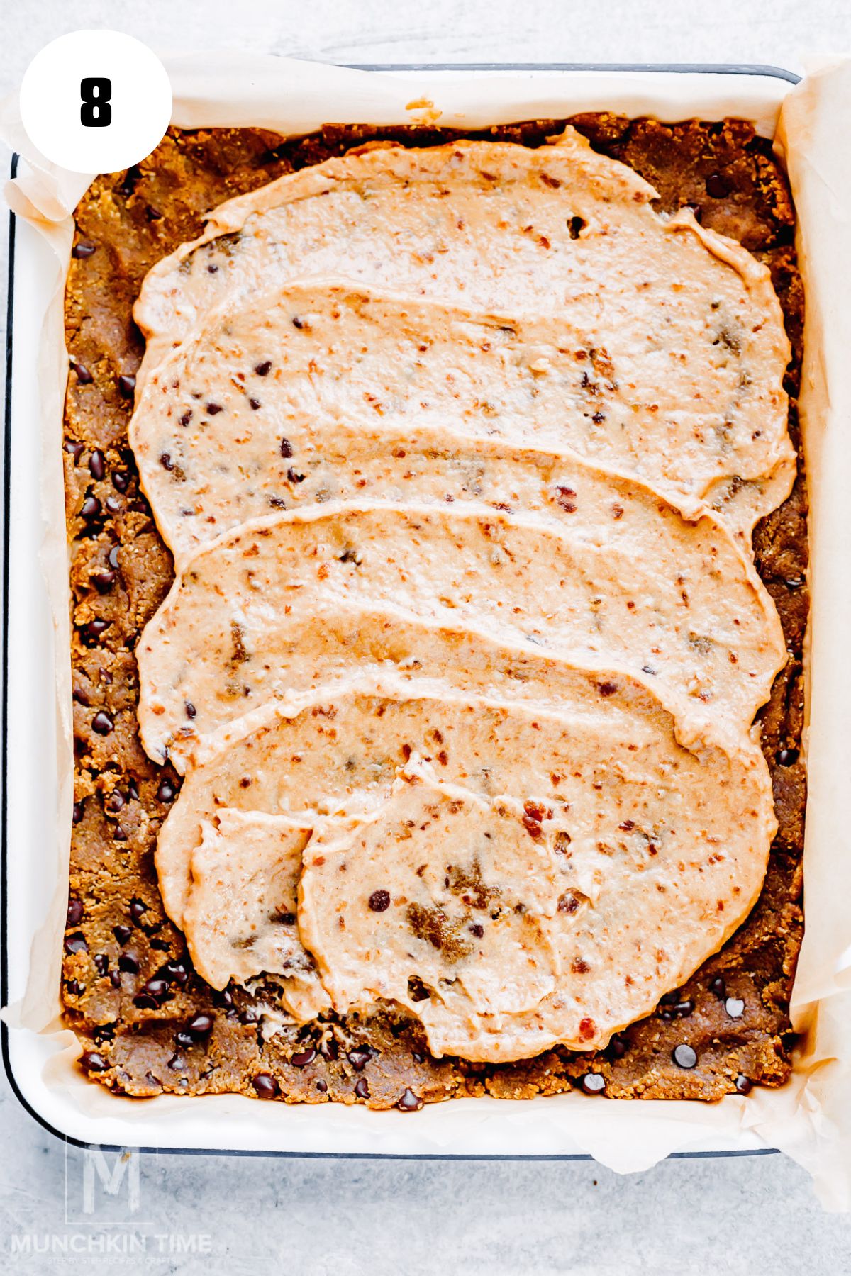 Spreading creamy date caramel over chilled cookie dough base